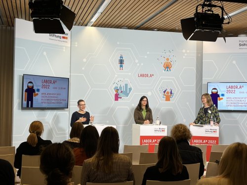 Foto des Podiums der Session, aus Perspektive des Publikums fotografiert. Von links nach rechts auf dem Podium: Elisa Rabe, Mara Kuhl, Alexandra Scheele.